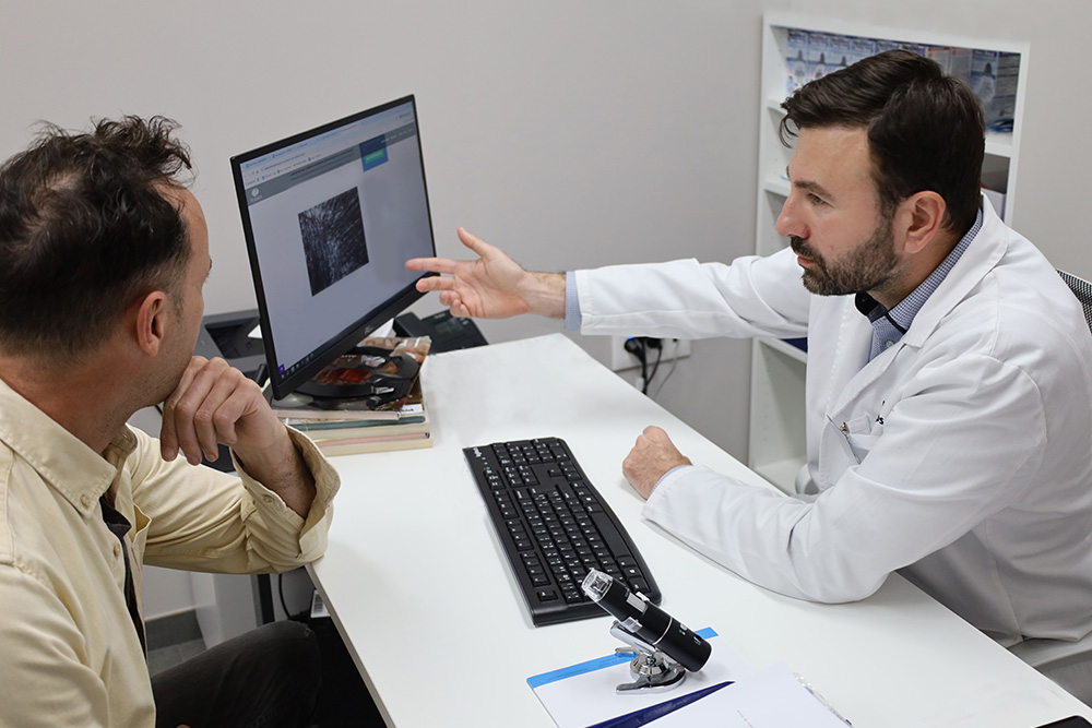 Dr. Leonidas Alevizos, cirujano especialista en tricología y microinjerto capilar en consulta con un paciente